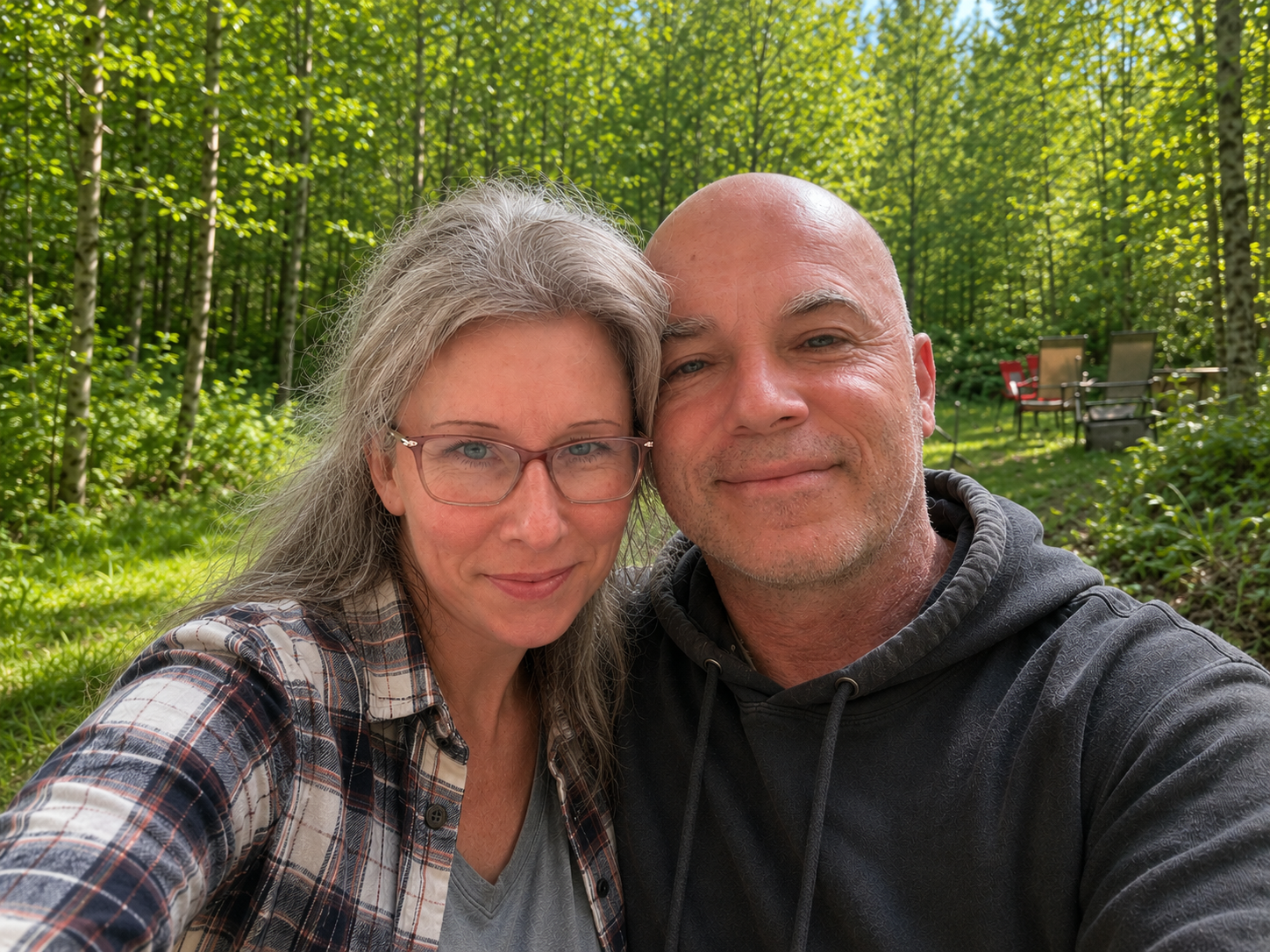 Stacie Rae and Jamie, creators of Blooming Rooster, sitting together among the trees on the farm